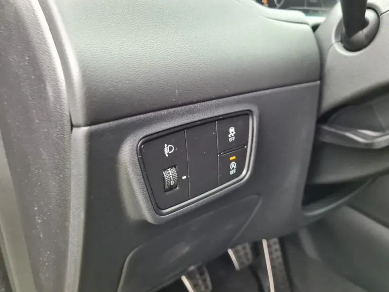 Gros plan sur les commandes de réglage des phares et aides à la conduite côté gauche du tableau de bord d'un Hyundai Tucson blanc polaire 2022.