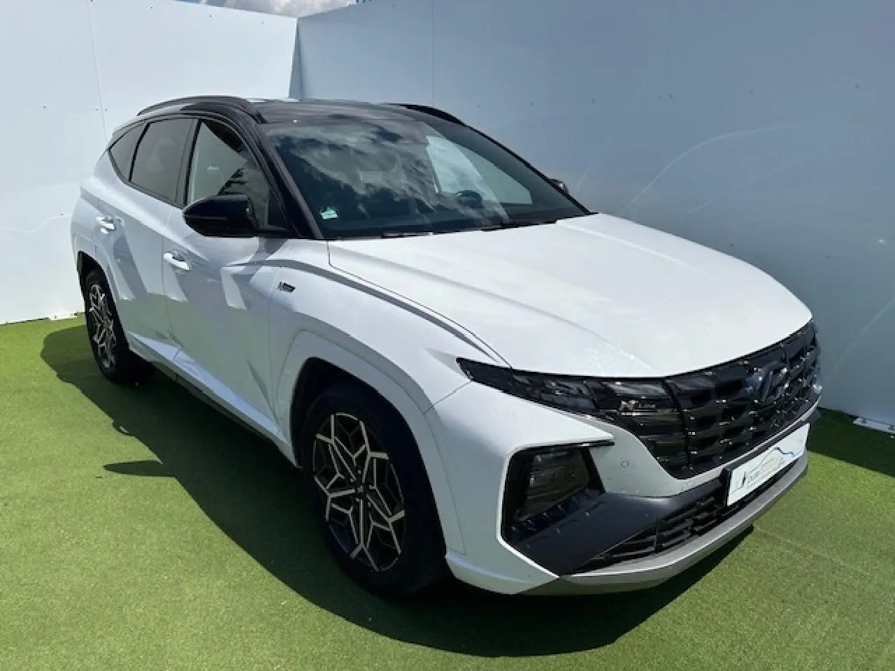 Vue 3/4 avant gauche du Hyundai Tucson blanc polaire avec toit noir et calandre noire distinctive N-LINE.