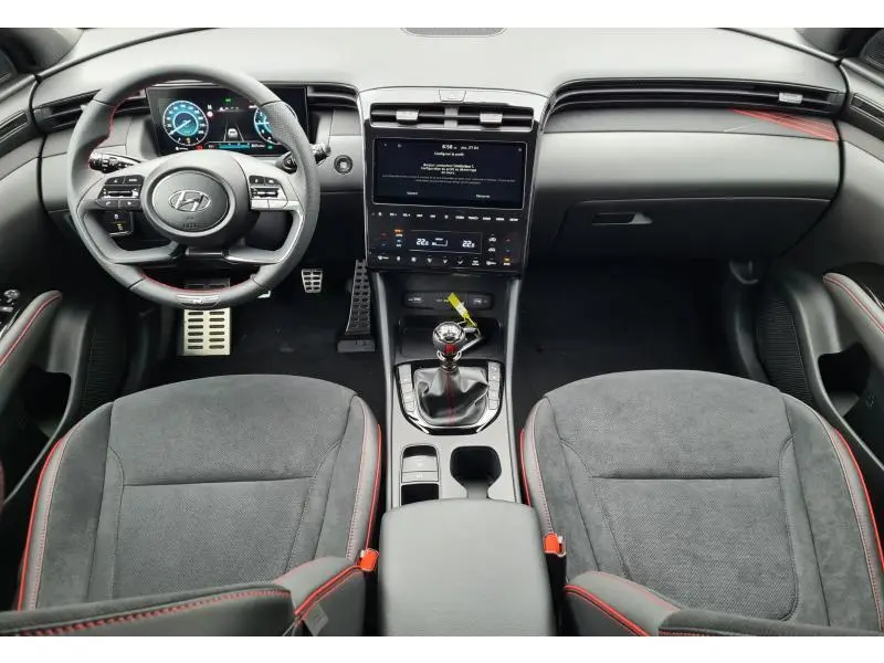Intérieur du Hyundai Tucson IV N-Line 2022, vue de face sur le tableau de bord et volant cuir noir avec surpiqûres rouges.