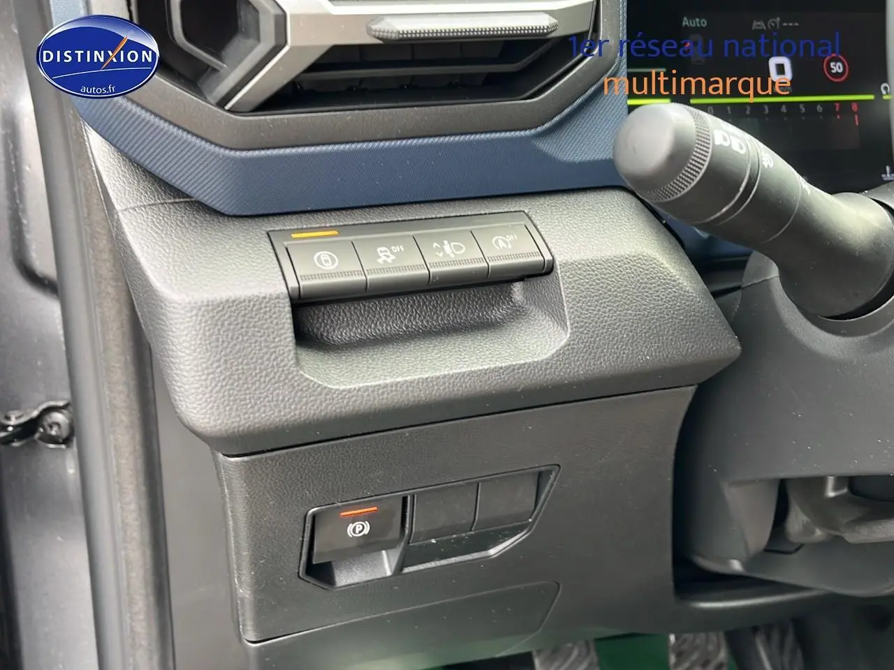 Détail du tableau de bord côté gauche du Dacia Duster gris schiste 2025 avec commandes d'aide à la conduite et frein à main électrique.