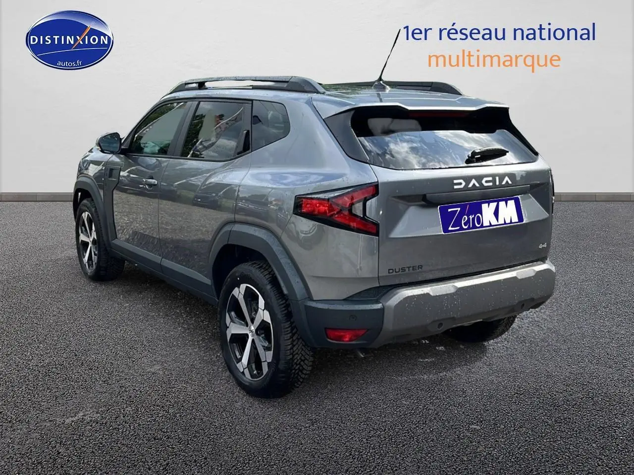 Vue 3/4 arrière droite du Dacia Duster gris schiste 2025 avec jantes alu et barres de toit noires.