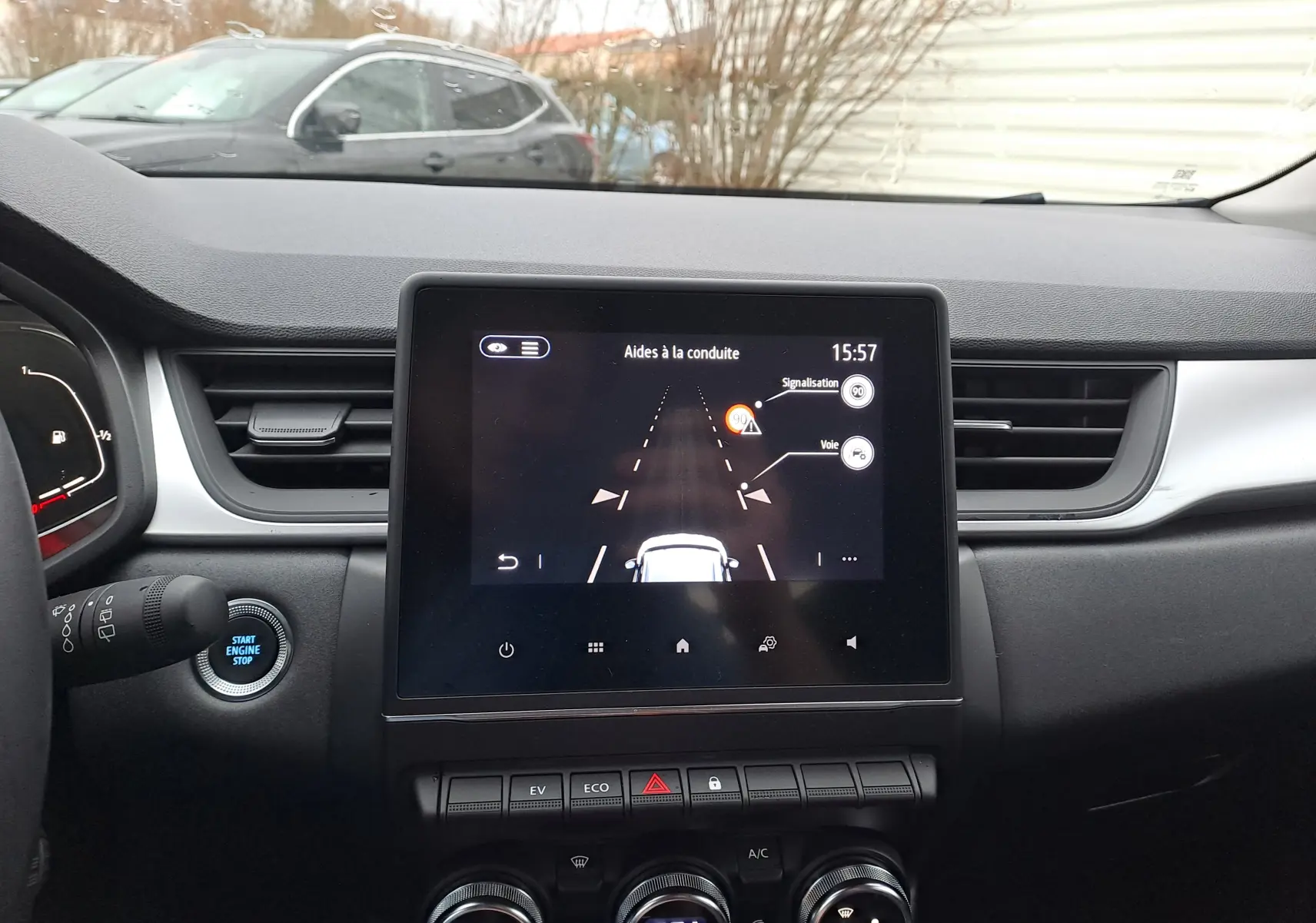 Vue intérieure du tableau de bord du Renault Captur gris, avec écran tactile central affichant les aides à la conduite.