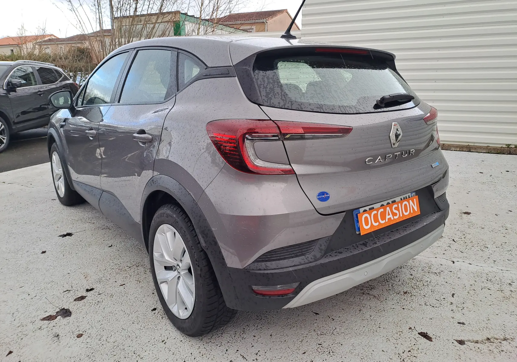 Vue 3/4 arrière droite d'un Renault Captur gris Cassiopée métallisé avec feux arrière LED et plaque occasion.