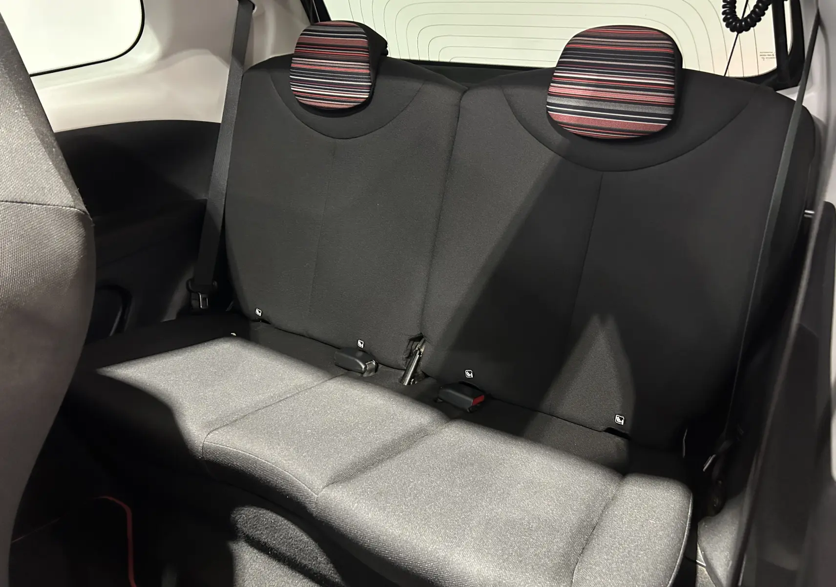 Vue intérieure arrière des sièges noirs avec appuie-têtes rayés de la Citroën C1 Airscape 2019.