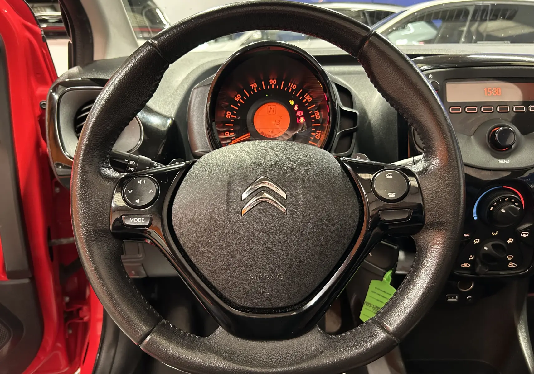 Vue rapprochée du volant noir de la Citroën C1 rouge de 2019 avec tableau de bord et commandes visibles.