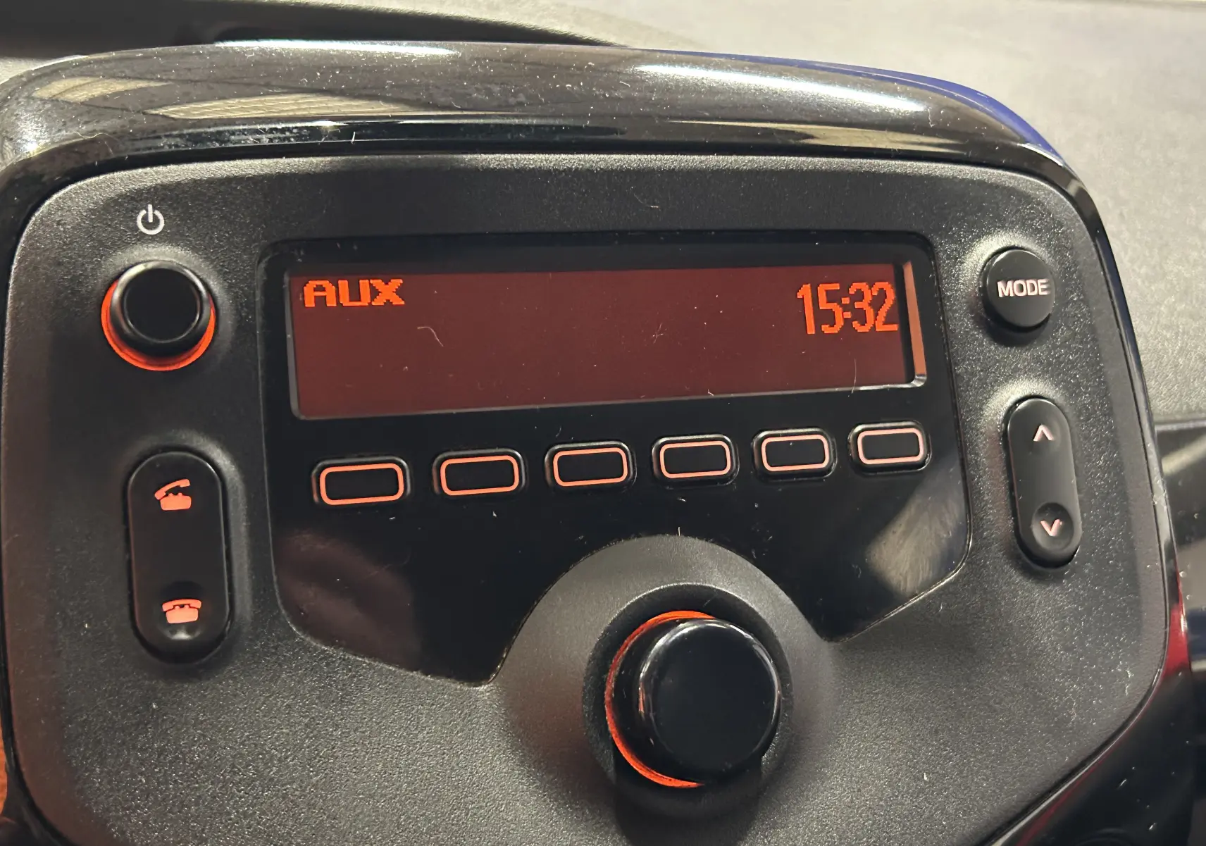 Gros plan sur l’autoradio noir de la Citroën C1 rouge, affichant l’heure 15:32 et la source AUX.