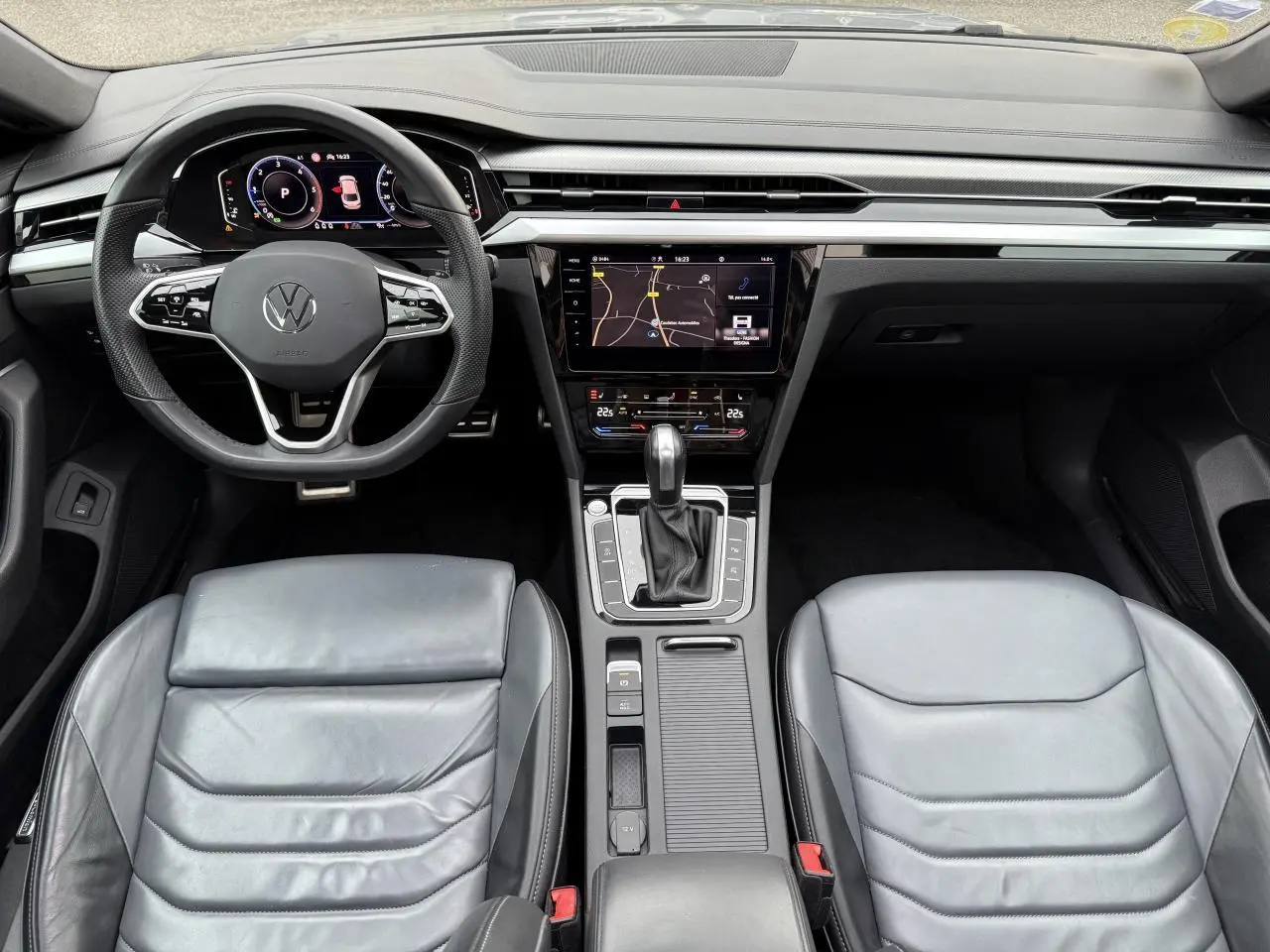 Vue intérieure frontale du tableau de bord et des sièges en cuir gris d'une Volkswagen Arteon 2021 avec écran tactile central.