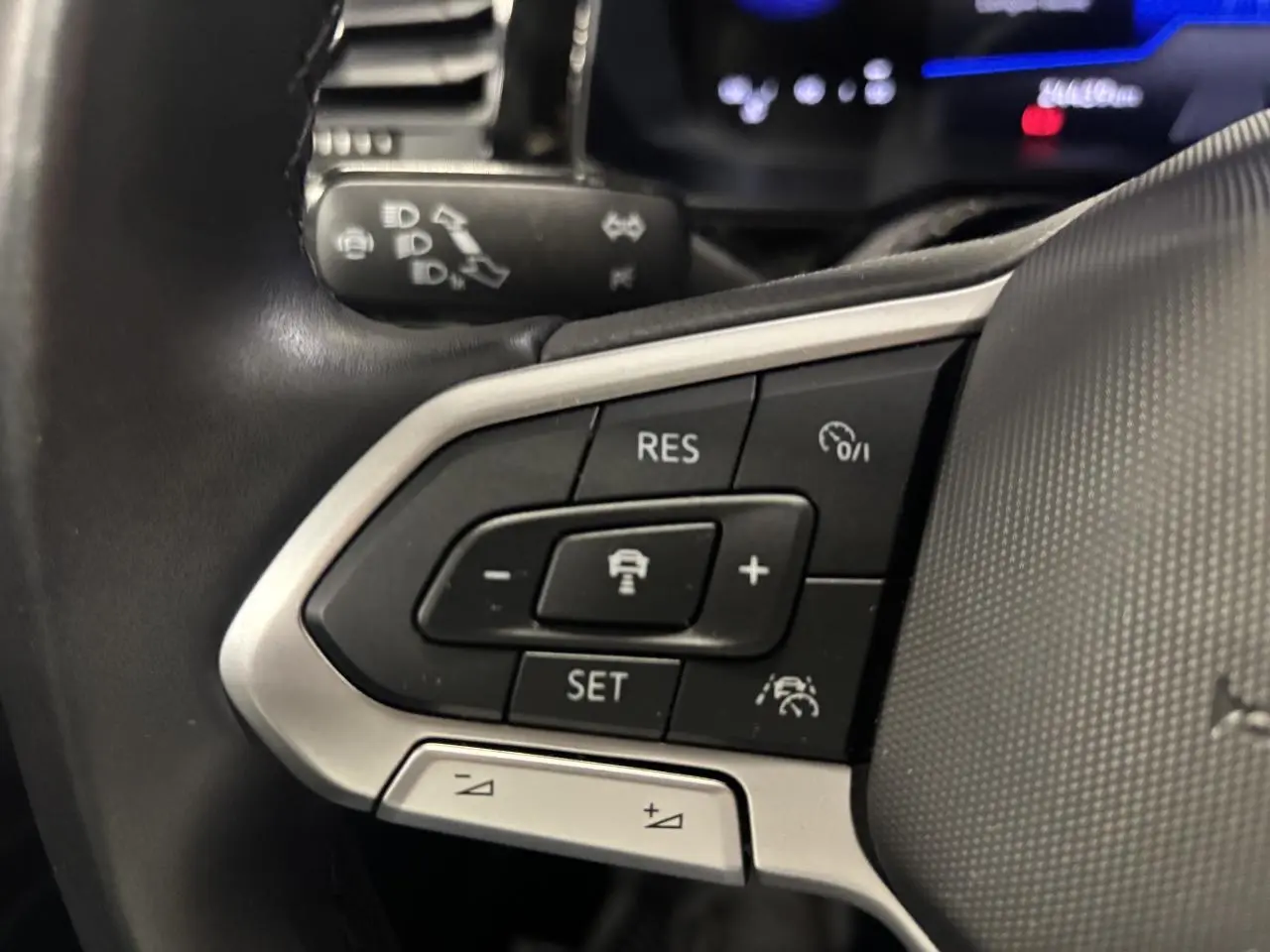 Gros plan sur les commandes du volant cuir multifonctions du Volkswagen Taigo 2023, boutons noirs et argentés.