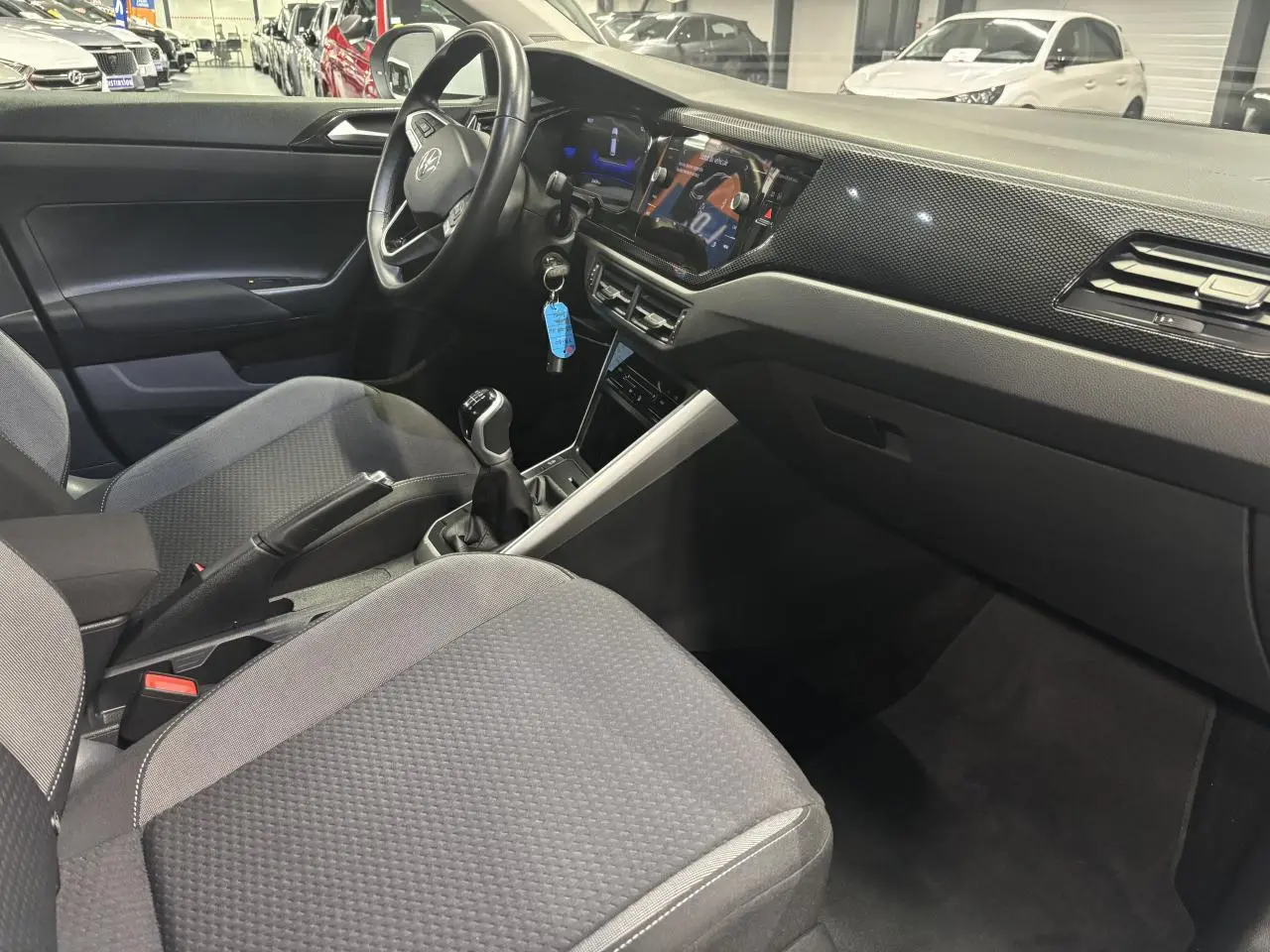 Vue intérieure côté conducteur du Volkswagen Taigo 2023 avec tableau de bord noir et volant cuir multifonctions.