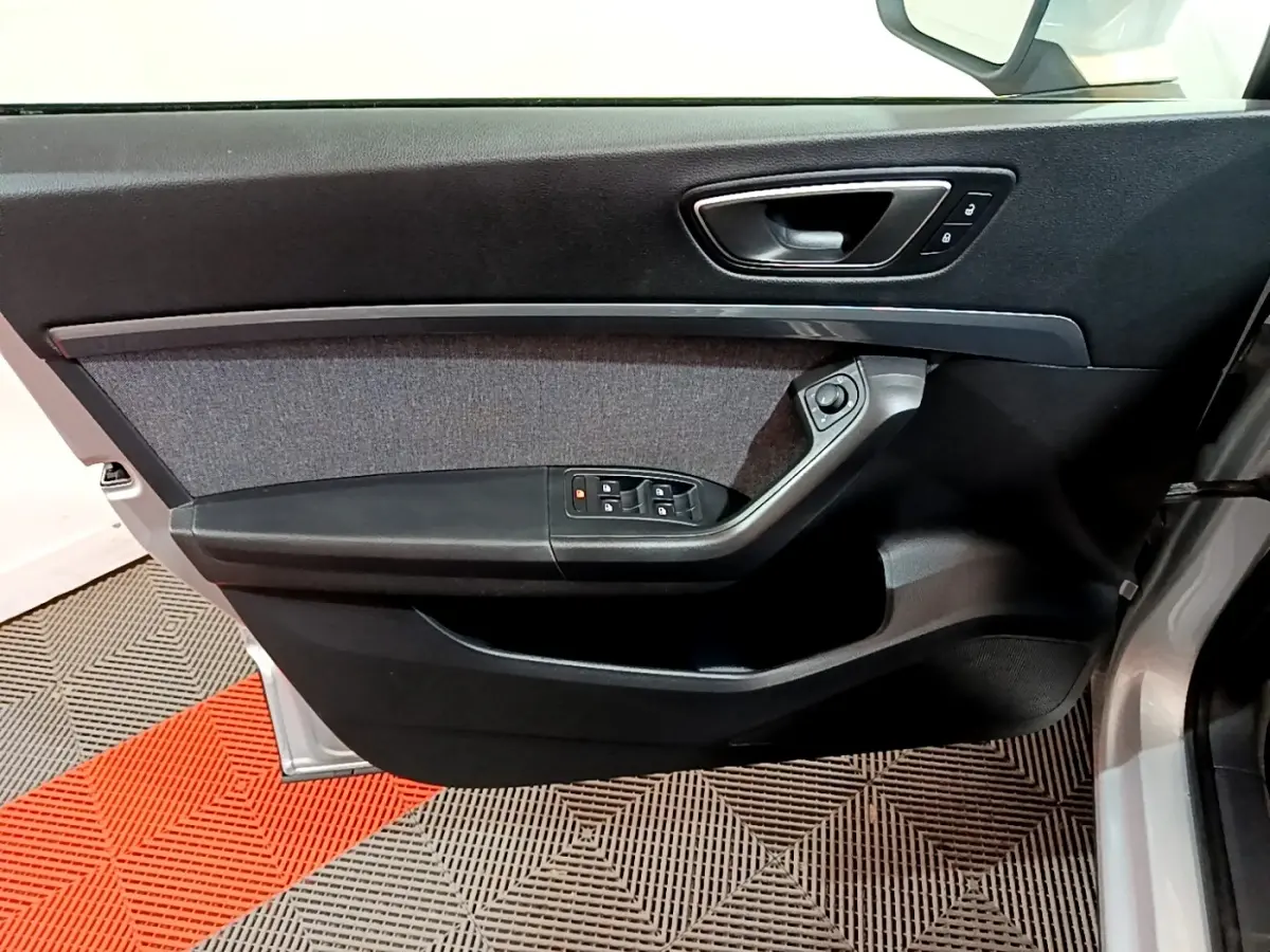 Vue intérieure côté gauche de la porte avant d'un SEAT Ateca gris clair avec commandes de vitres et verrouillage.