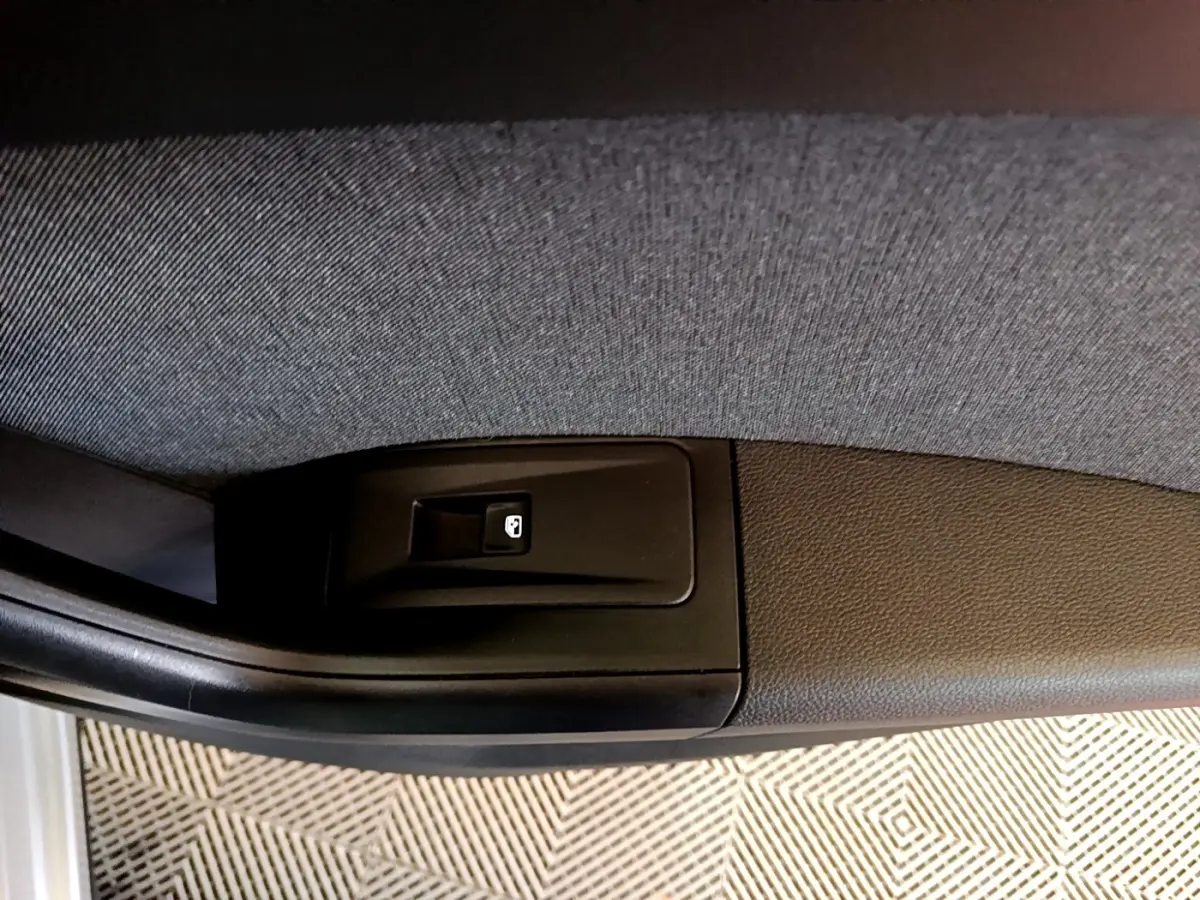 Gros plan sur le bouton de verrouillage de porte côté conducteur du SEAT Ateca gris clair, intérieur tissu et plastique noir.