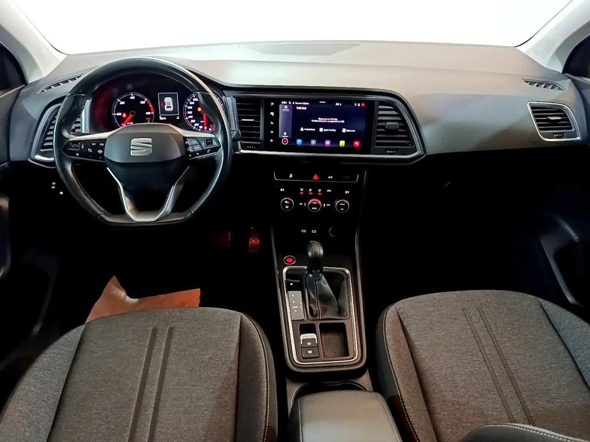 Vue intérieure avant du tableau de bord et volant cuir noir du SEAT Ateca 2022 avec écran tactile central allumé.