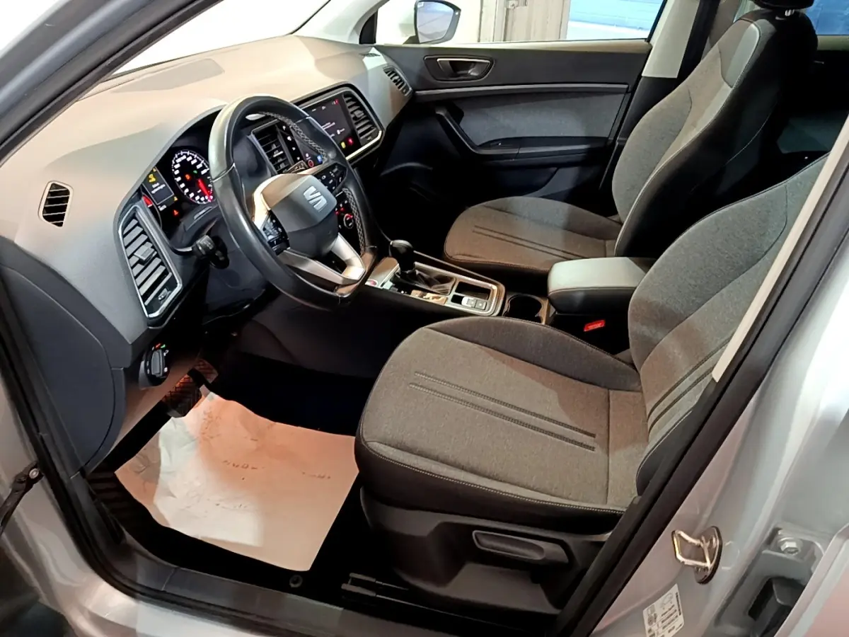 Vue intérieure côté conducteur du SEAT Ateca gris clair 2022, avec sièges tissu gris et tableau de bord moderne.