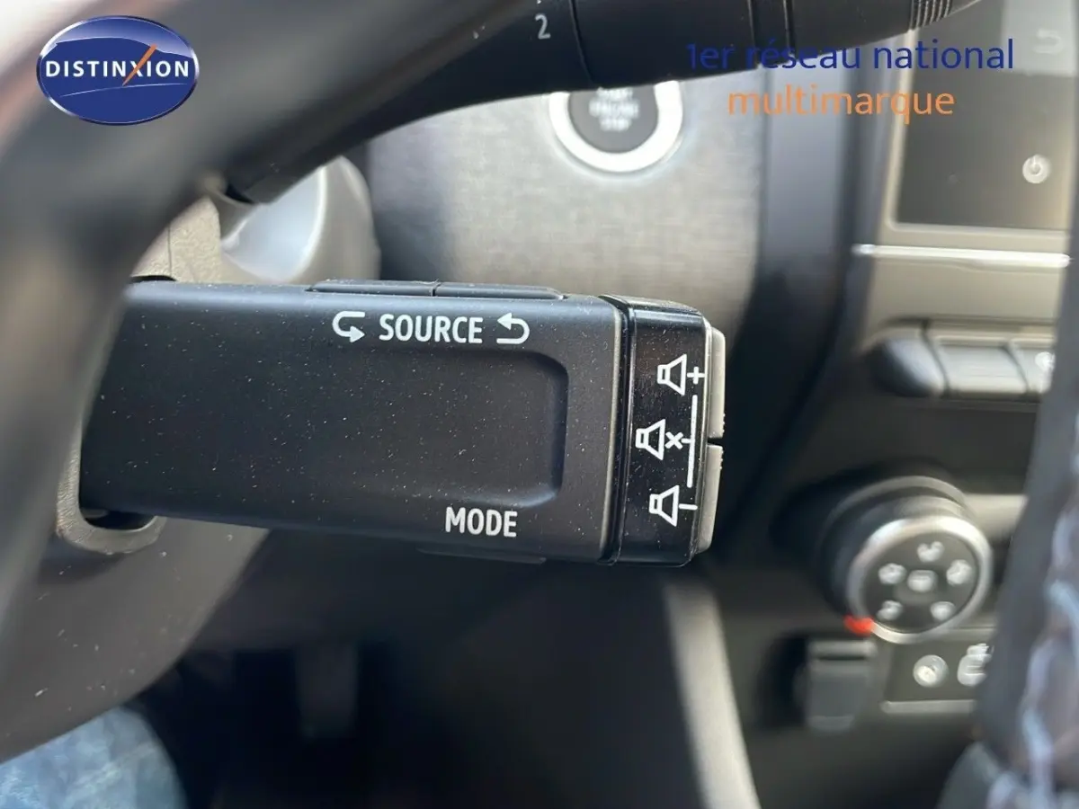 Gros plan sur la commande au volant noir de la Renault Clio Evolution Blue dCi 100, intérieur sombre.