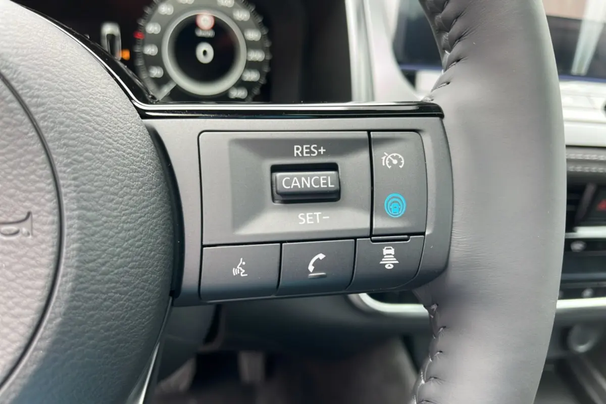 Gros plan sur les commandes multifonctions du volant cuir du Nissan Qashqai E-POWER 205 Tekna Plus 2026.
