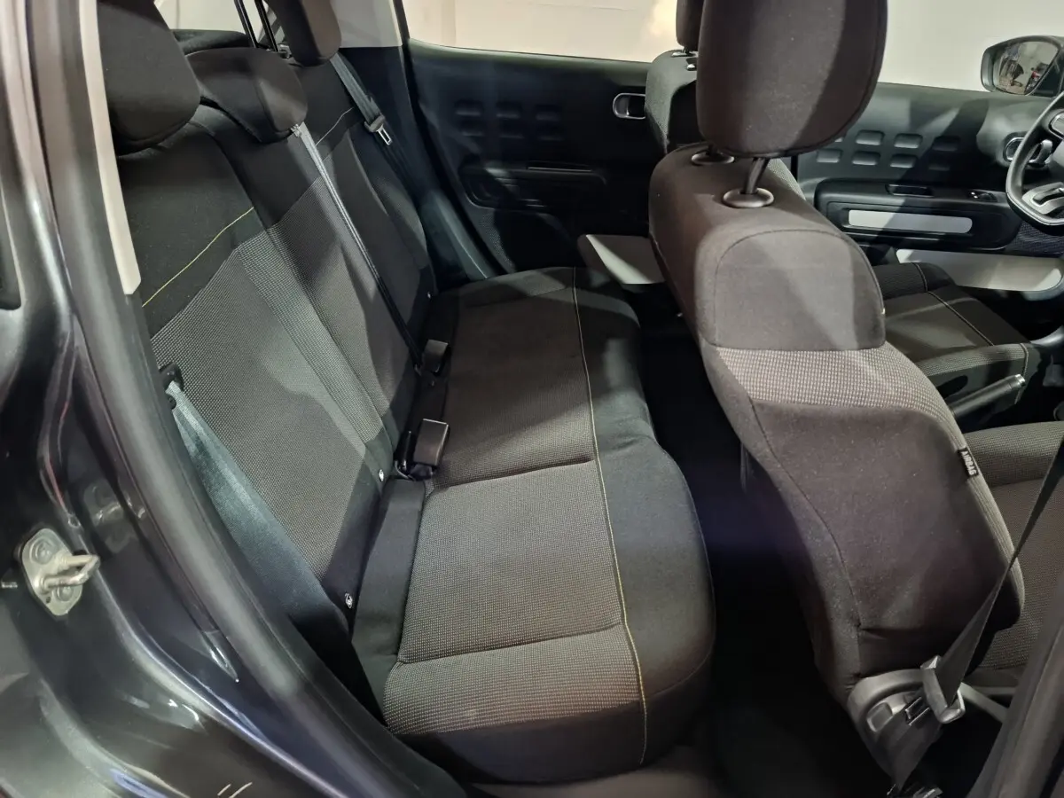 Vue intérieure côté arrière gauche de la Citroën C3 2024 gris foncé, montrant les sièges tissu et la porte ouverte.