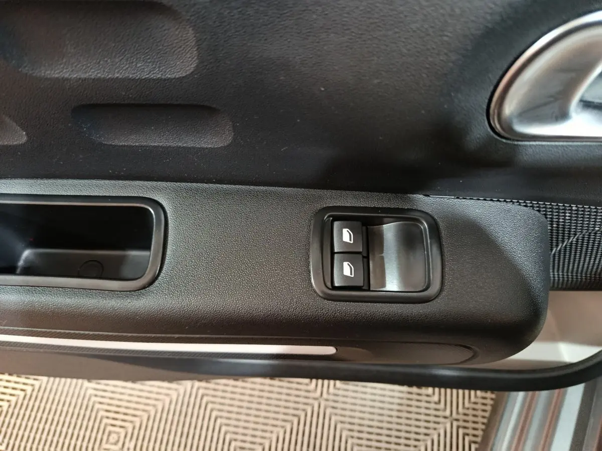 Gros plan sur les commandes des vitres électriques côté conducteur de la Citroën C3 gris foncé, intérieur noir.