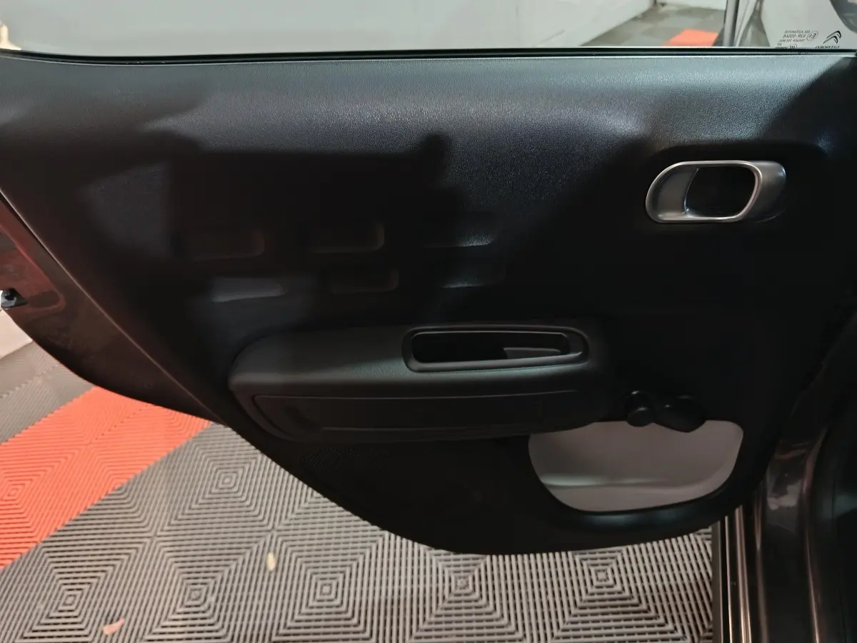 Vue intérieure de la porte arrière droite gris foncé de la Citroën C3 2024 avec poignée et commande de vitre manuelle.