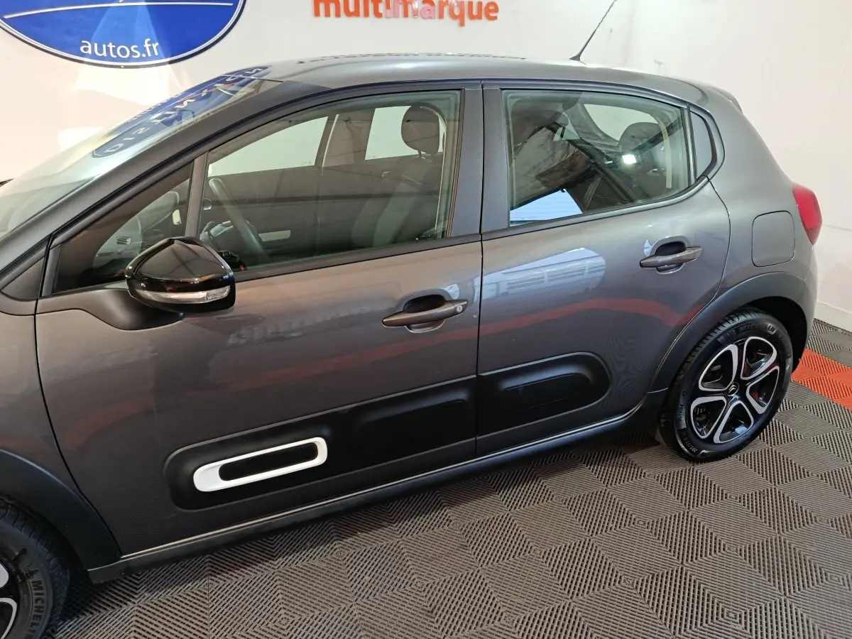 Vue de profil côté gauche d'une Citroën C3 2024 gris foncé avec protections latérales noires et jantes stylisées.