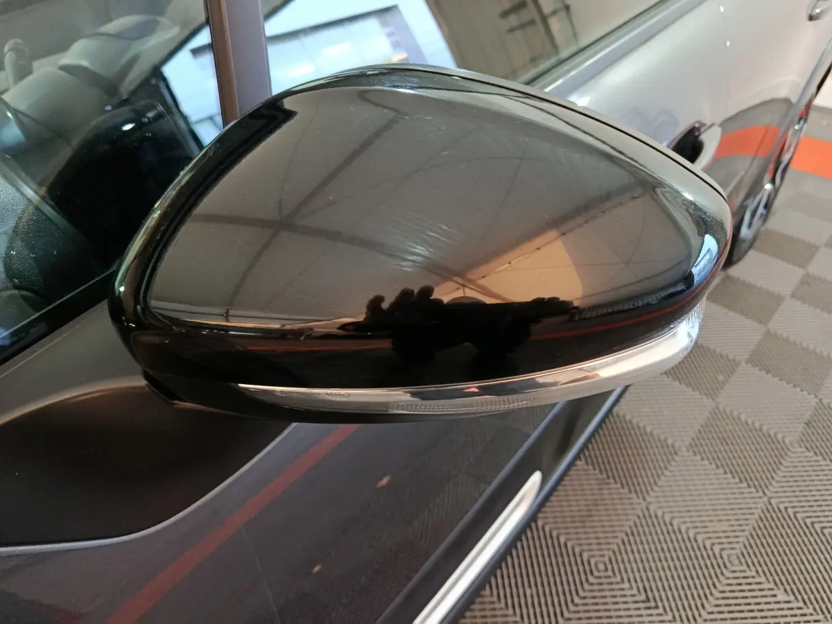 Gros plan sur le rétroviseur droit noir brillant d’une Citroën C3 gris foncé, avec clignotant intégré visible.