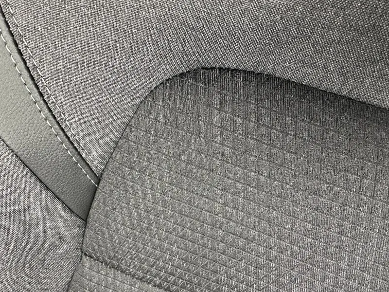 Détail du tissu gris texturé et surpiqûres contrastantes sur un siège intérieur du Nissan Qashqai Hybrid e-POWER 2025.