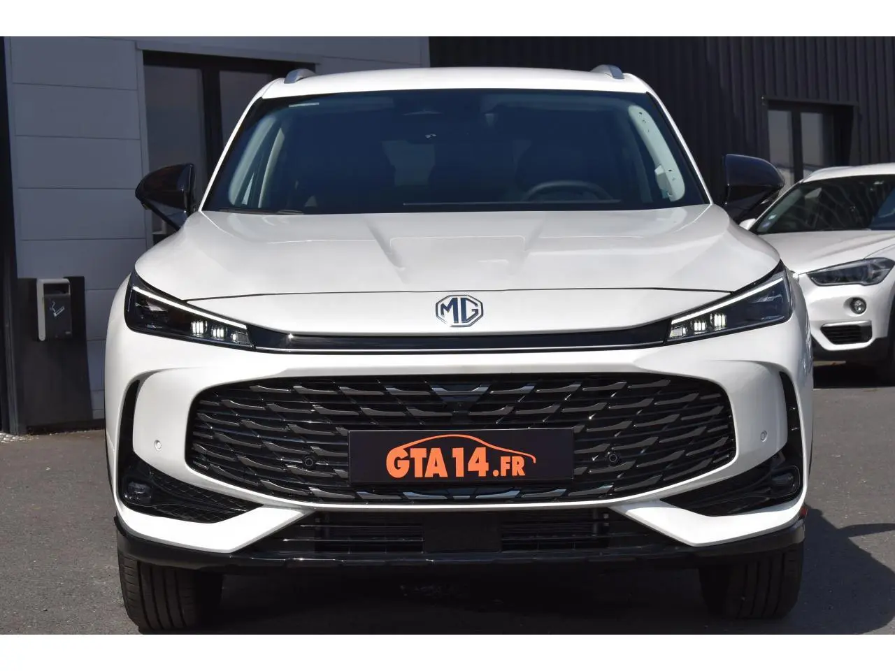 Vue frontale d'un MG Motor EHS blanc 2026 avec calandre noire large et phares LED fins intégrés.