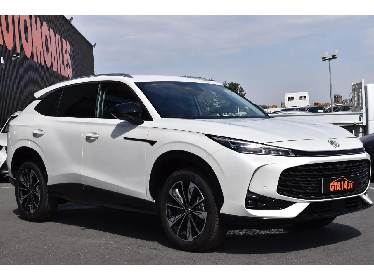 Vue 3/4 avant droit du SUV blanc MG EHS 1.5 Hybrid+ Luxury avec calandre noire et jantes stylisées.