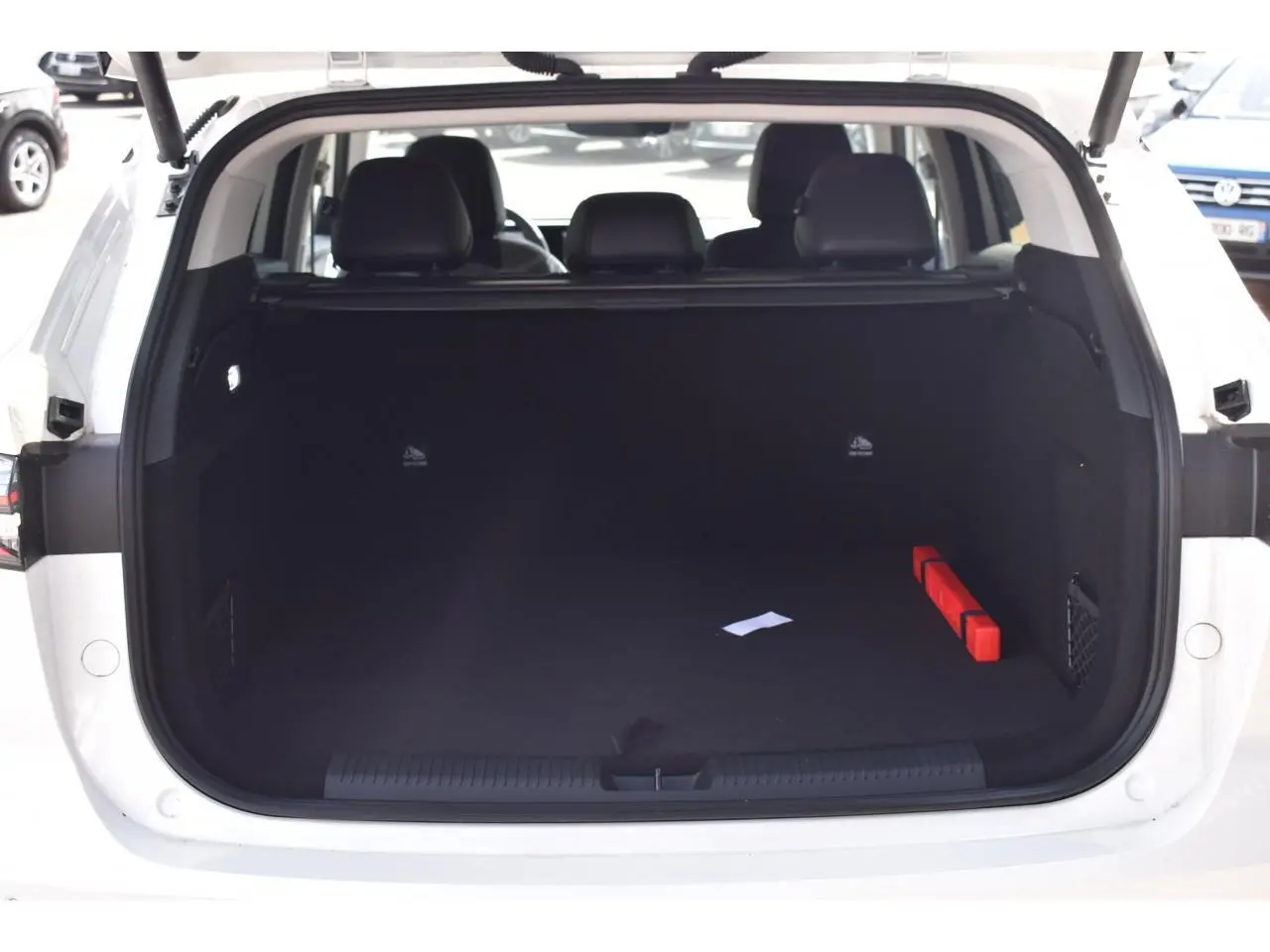 Coffre ouvert d’un MG MOTOR EHS blanc, vue arrière, montrant un espace de chargement vide avec un triangle de signalisation rouge.