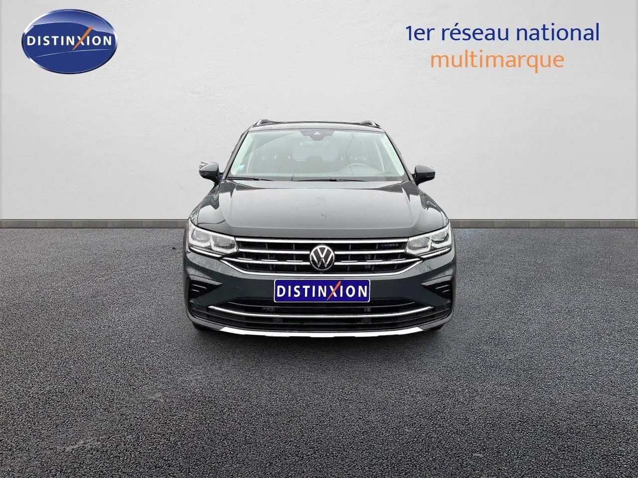 Vue frontale d'un Volkswagen Tiguan gris lunaire 2022 hybride rechargeable avec calandre chromée et logo VW visible.