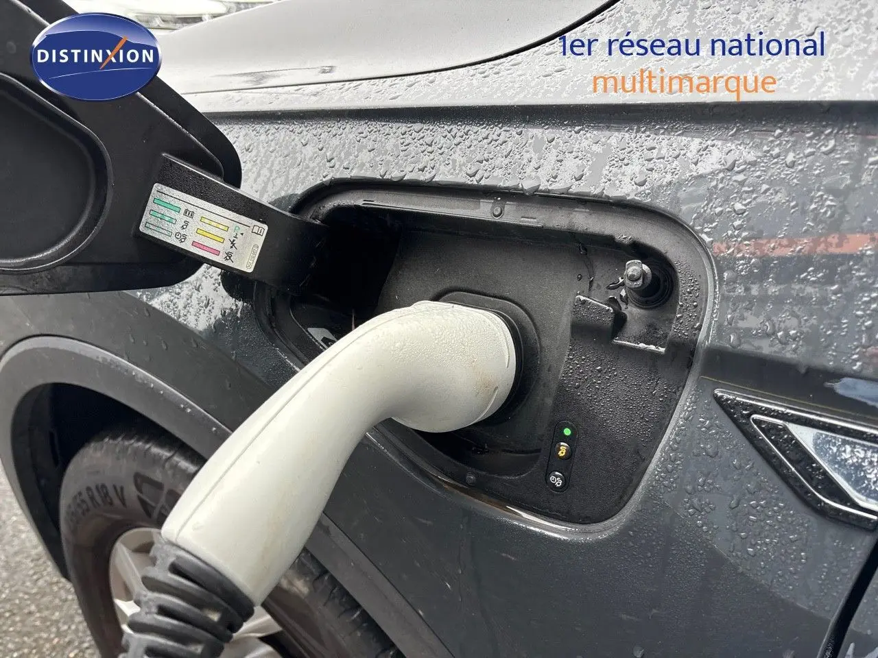 Prise de recharge en gros plan sur le côté gauche d'un Volkswagen Tiguan gris lunaire hybride rechargeable sous la pluie.