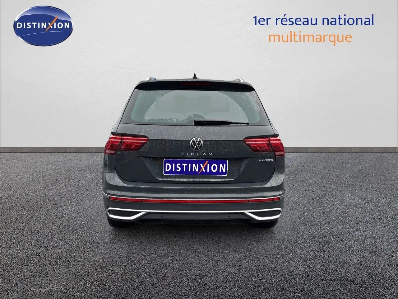 Vue arrière d'un Volkswagen Tiguan gris lunaire hybride rechargeable avec feux LED et logo distinctif visible.