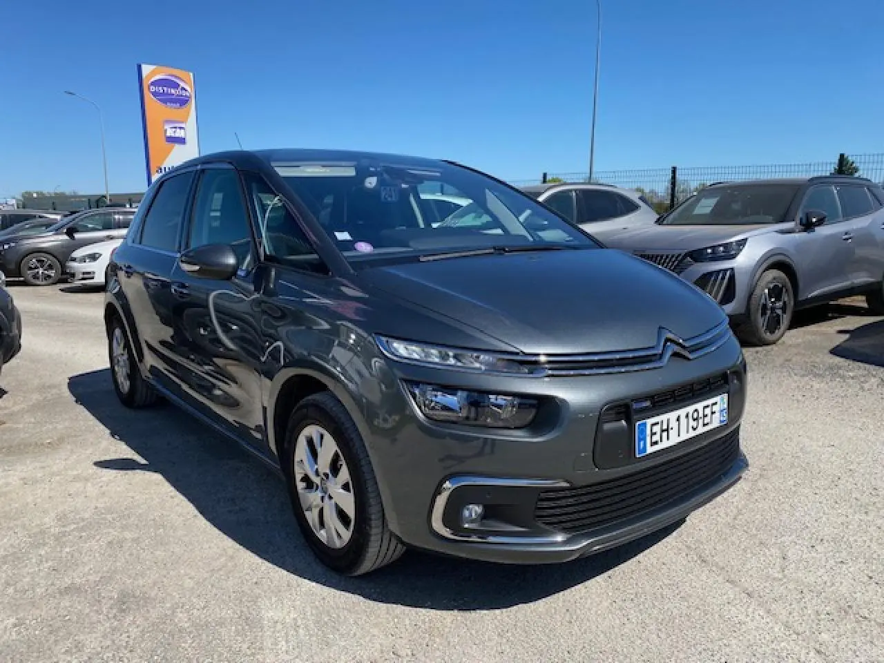 Citroën C4 Picasso gris shark vue 3/4 avant droit, avec feux LED et jantes alliage 16 pouces visibles.