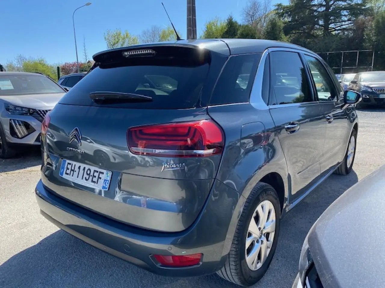 Vue 3/4 arrière droite d'une Citroën C4 Picasso gris shark avec feux arrière LED et jantes alliage 16 pouces.