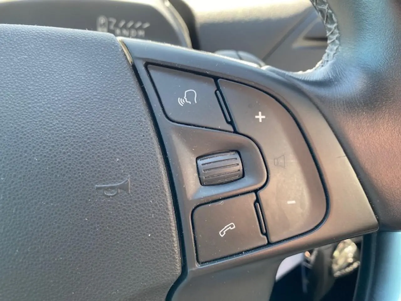 Gros plan sur les commandes vocales et volume au volant cuir noir du Citroën C4 Picasso gris Shark de 2016.