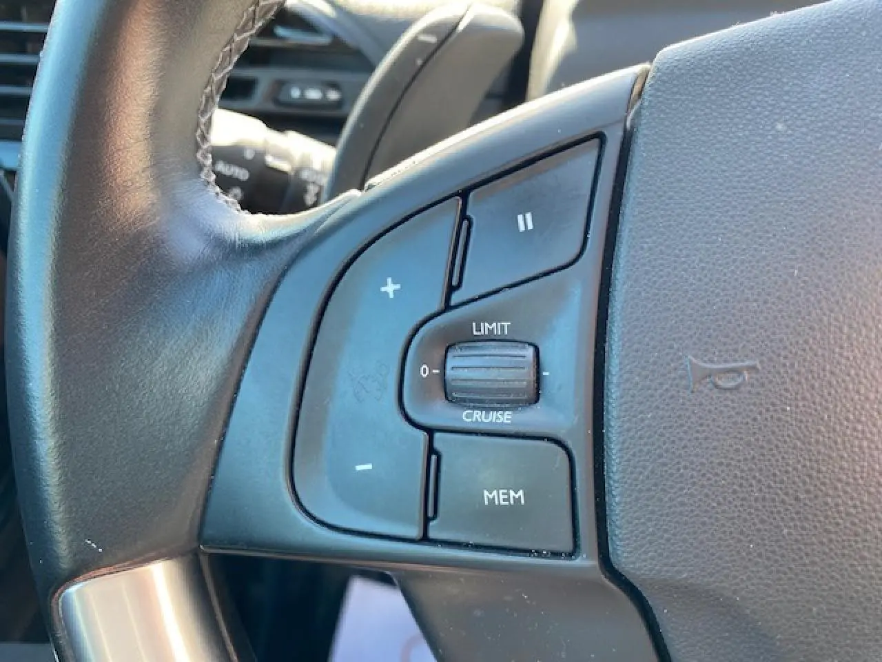 Gros plan sur les commandes de régulateur de vitesse au volant cuir d'une Citroën C4 Picasso gris Shark de 2016