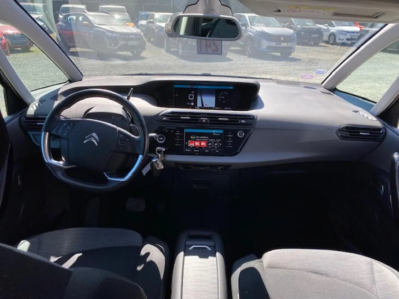 Vue intérieure avant du Citroën C4 Picasso 2016, tableau de bord gris avec écran tactile et volant multifonction.