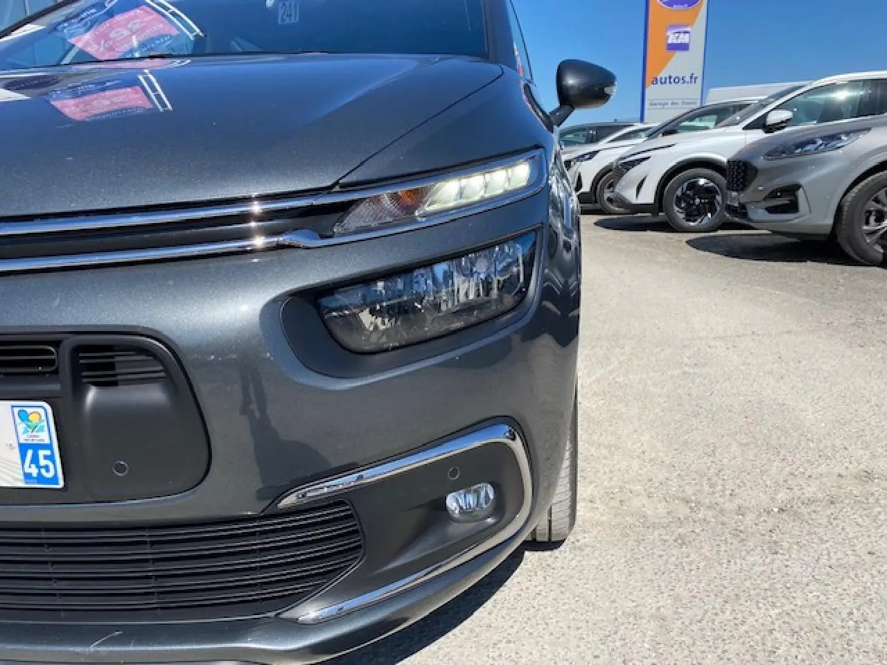 Gros plan sur l'avant droit d'une Citroën C4 Picasso gris shark avec phares LED et calandre chromée.