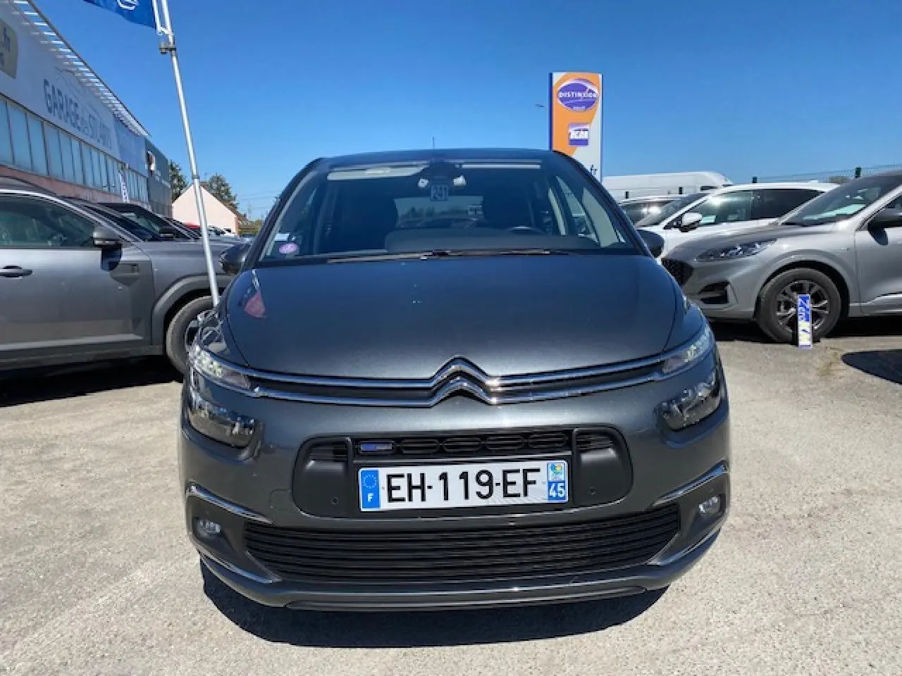 Vue avant d'une Citroën C4 Picasso gris shark 2016 avec calandre chromée et phares LED allumés.
