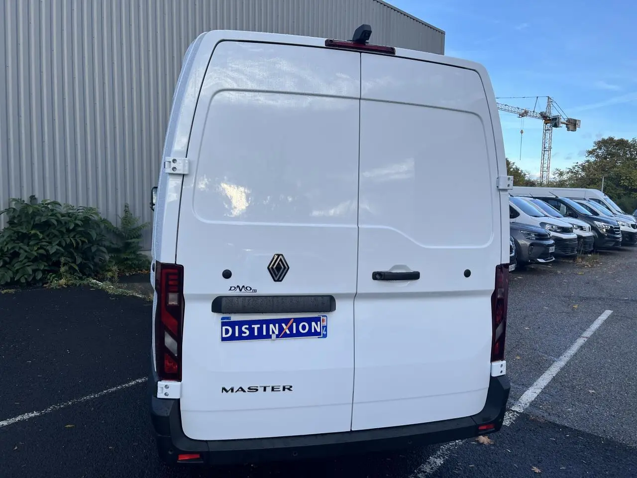 Vue arrière d’un utilitaire Renault Master blanc avec portes arrière tôlées et logo noir sur parking.