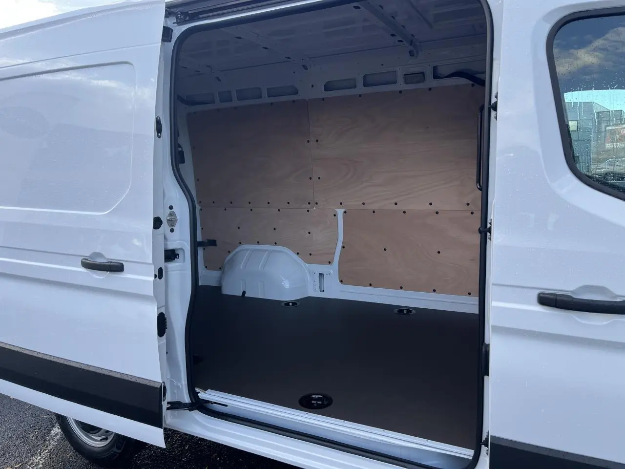 Vue latérale droite du Renault Master blanc 2025 avec porte coulissante ouverte montrant l'intérieur aménagé en plancher bois.