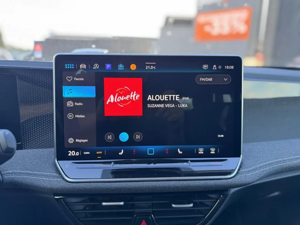 Écran tactile 12,9" du tableau de bord d'une Volkswagen Passat SW noire, affichant la radio Alouette.