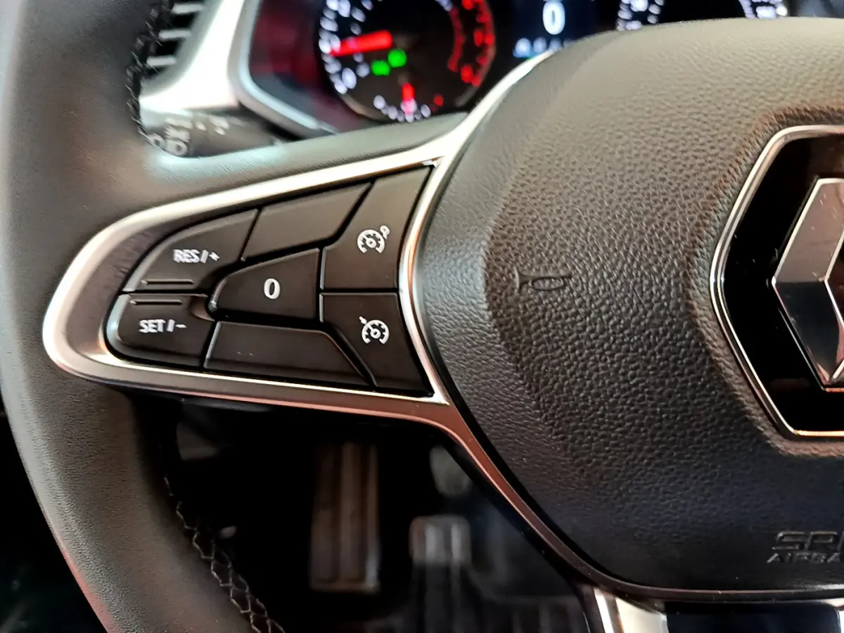 Gros plan sur le volant noir du Renault Captur Business TCe 90 2021, avec commandes de régulateur de vitesse visibles à gauche.