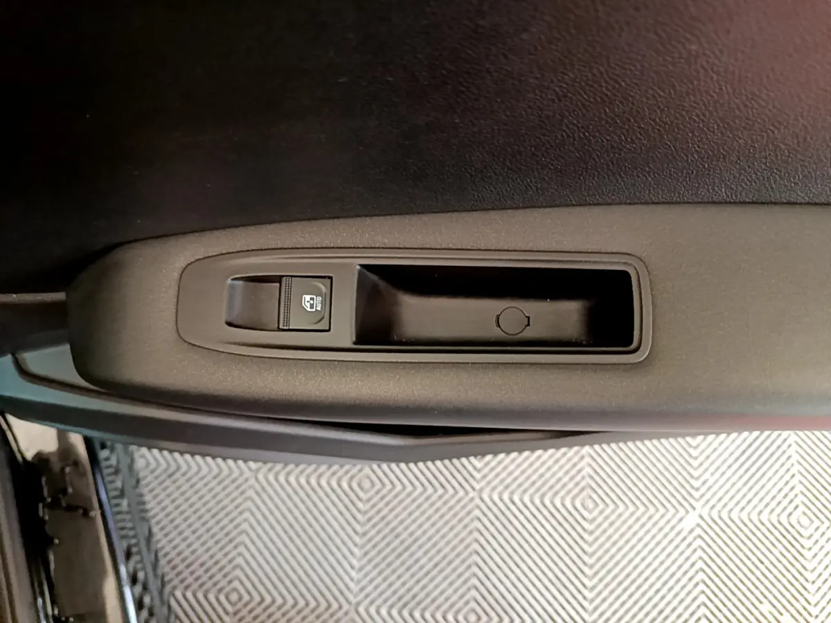 Gros plan sur la commande de lève-vitre côté gauche de la porte d’une Renault Captur Business TCe 90 noire de 2021.