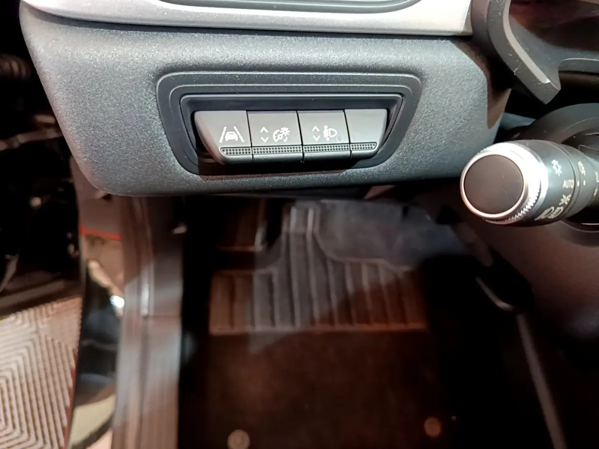 Gros plan sur les commandes d'assistance à la conduite sous le tableau de bord du Renault Captur noir 2021.