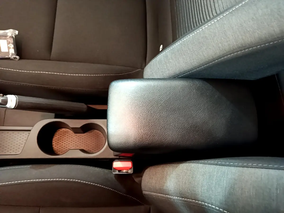 Vue plongeante sur l'accoudoir central noir et les sièges en tissu gris du Renault Captur Business TCe 90 2021.