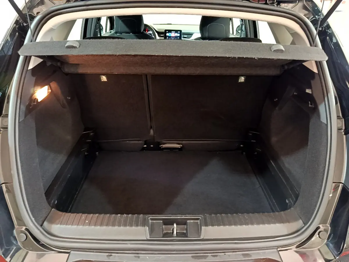 Coffre ouvert noir du Renault Captur Business TCe 90 2021, vue arrière avec tablette de cachette relevée.