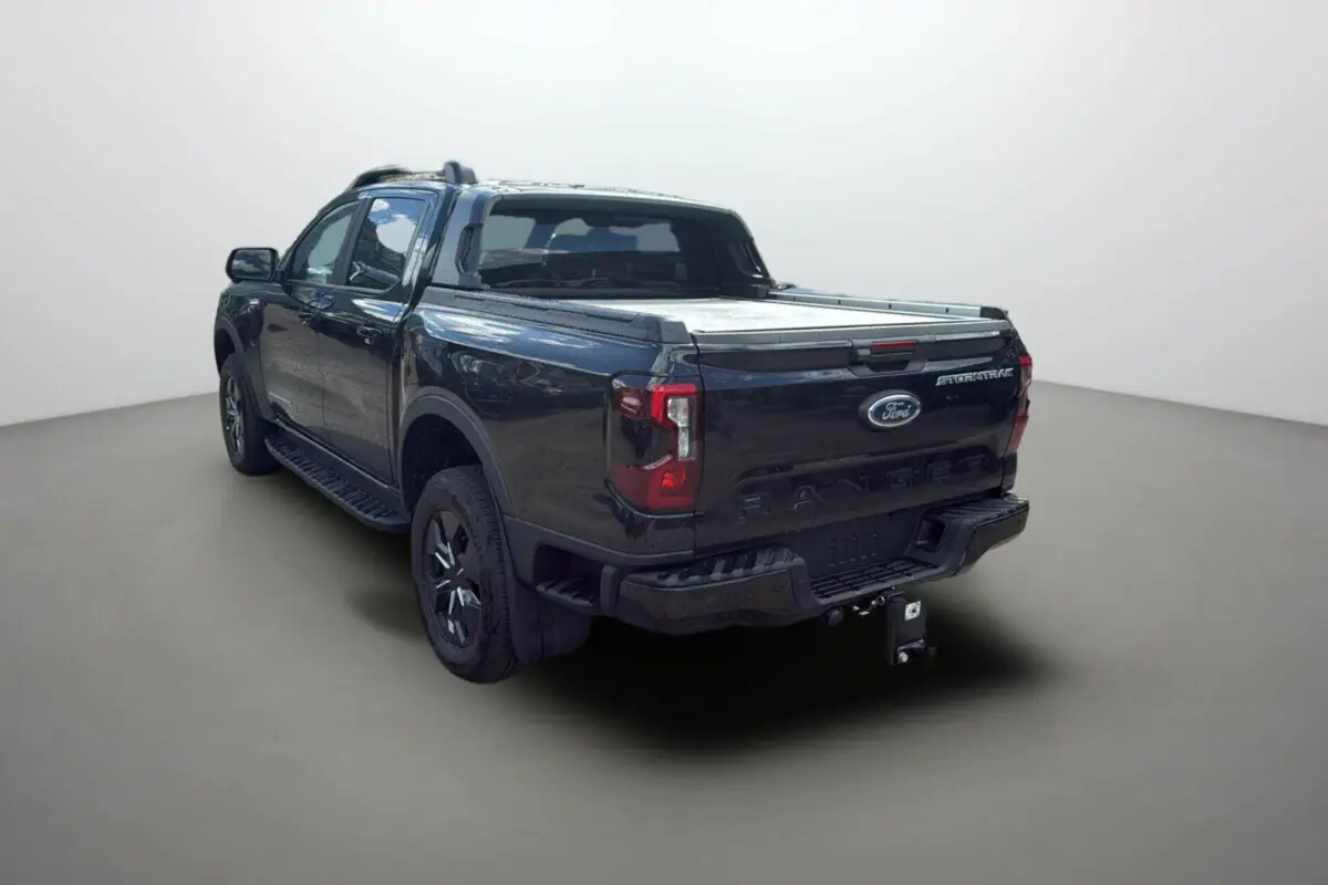 Vue 3/4 arrière du Ford Ranger 2025 noir agate avec benne couverte et badge Stormtrak visible sur la porte de coffre.