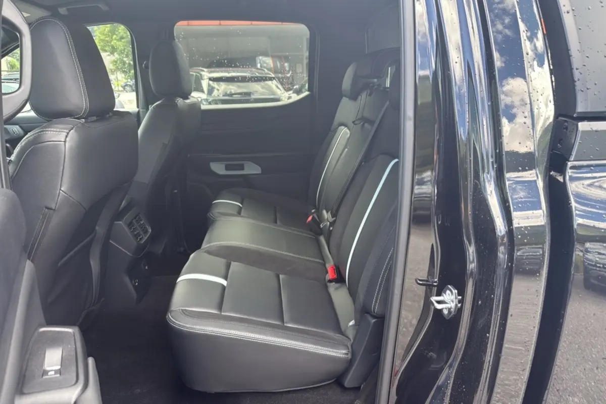 Vue intérieure arrière côté droit du Ford Ranger 2025 noir agate, montrant les sièges en cuir noir avec surpiqûres blanches.