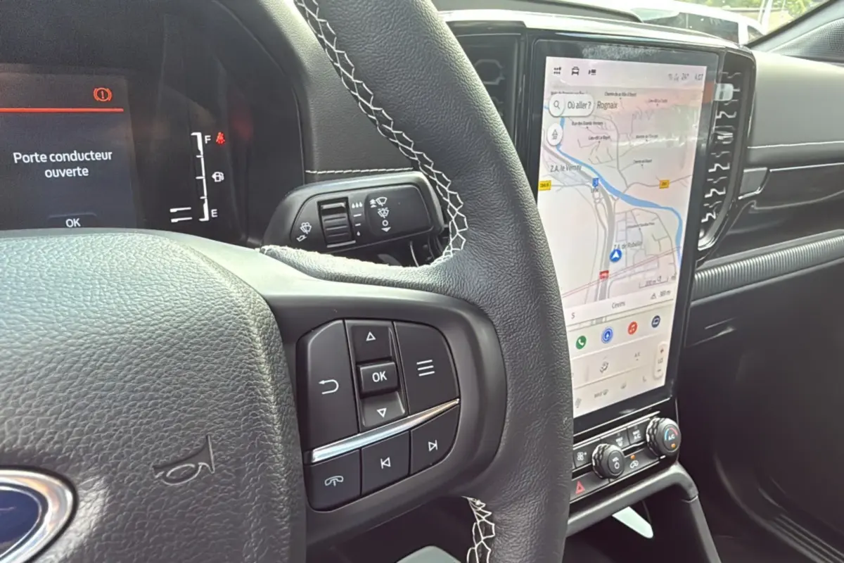 Vue rapprochée du volant et de l'écran tactile du Ford Ranger 2025 noir agate, affichant la navigation et le tableau de bord digital.