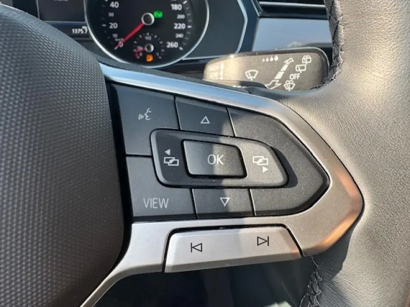 Gros plan sur les commandes multifonctions à droite du volant cuir d'une Volkswagen Passat SW gris manganèse 2022.